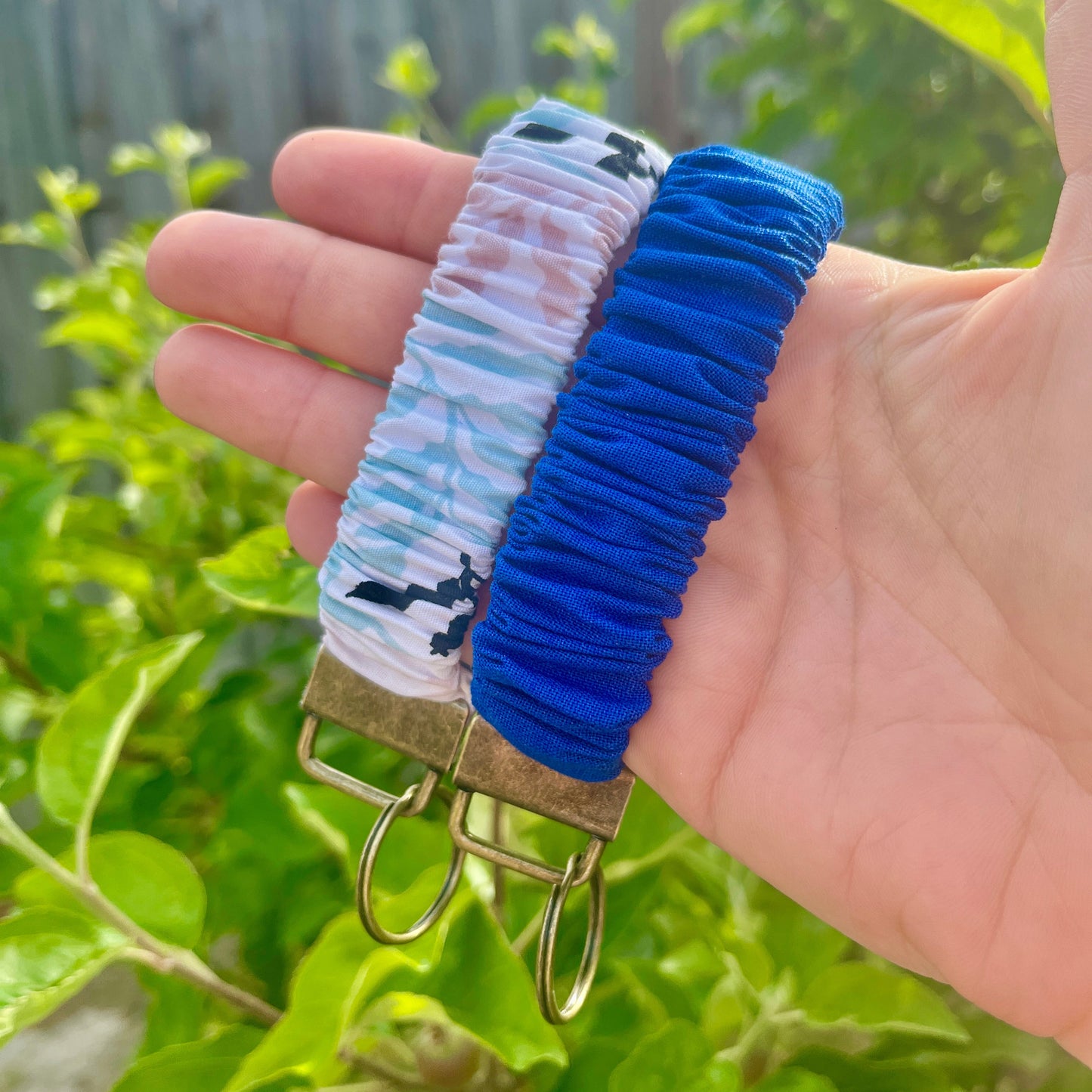 Sleutelhangers in de vorm van een Scrunchie voor om je pols. van stof en elastiek. Met stoffen bladeren patroon.in pastel roze, blauw en zwart. En een cobalt blauwe. Met bronskleurige klem/ring. Handgemaakt door Studio Dwarsdenker.