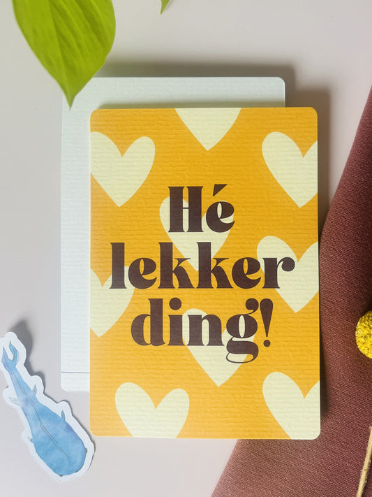 Ansichtkaart in oker gele tint, met pastel gele harten en de tekst: Hé lekker ding. Ontwerp door Studio Dwarsdenker