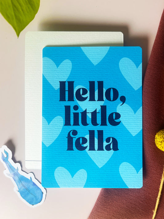 Ansichtkaart in fel blauwe tint, met pastel blauwe harten en de tekst: Hello, Little fella. Ontwerp door Studio Dwarsdenker