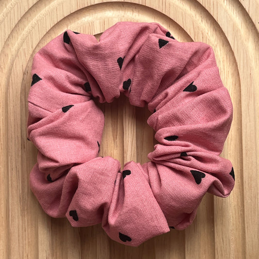 Haar scrunchie van oud roze poplin katoen met kleine zwarte hartjes. Elastisch en geschikt om een staart of knot vast te maken. Handgemaakt door Studio Dwarsdenker