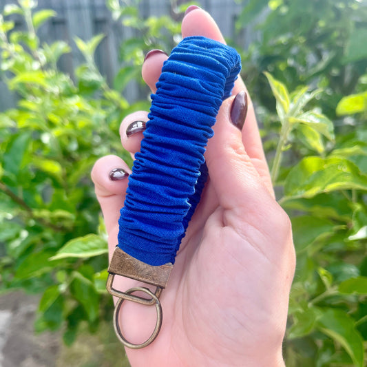 Sleutelhanger in de vorm van een  Scrunchie voor om je pols. Van stof met elastiek in cobalt blauw. Met bronskleurige klem/ring. Handgemaakt door Studio Dwarsdenker.
